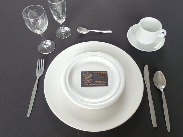 Assiette, couverts et verres dressés sur nappe noire