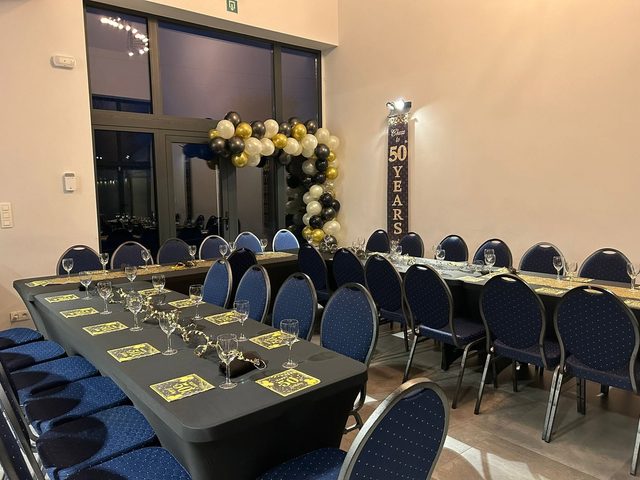 Salle dressée pour un anniversaire avec arche de ballons noir et or