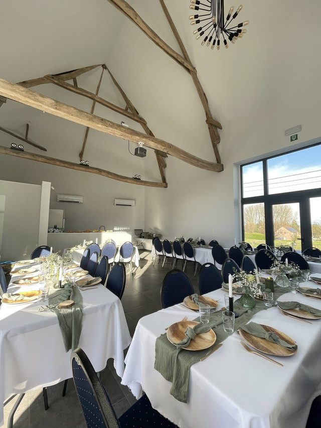 Table dressée sous la charpente : nappes blanches et chemins de table sauge